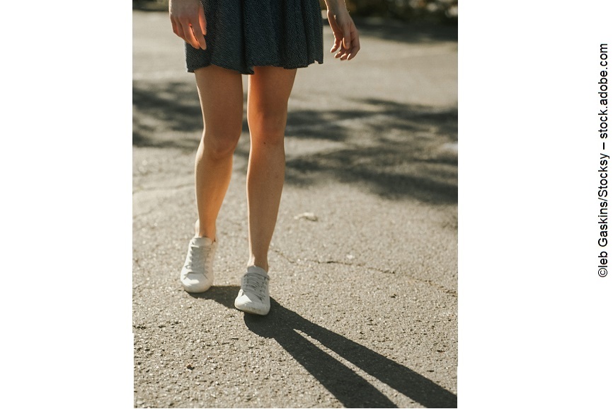 Die Beine einer Frau, die draußen spazieren geht. 